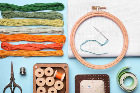 Flat lay composition with embroidery accessories on light blue background