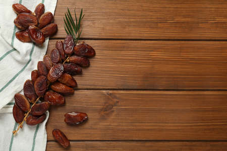 Branch with sweet dried dates and green leaf on wooden table, flat lay. Space for textの写真素材