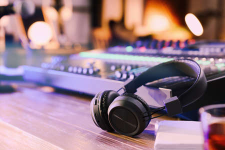 Headphones and professional mixing console on table in radio studioの写真素材