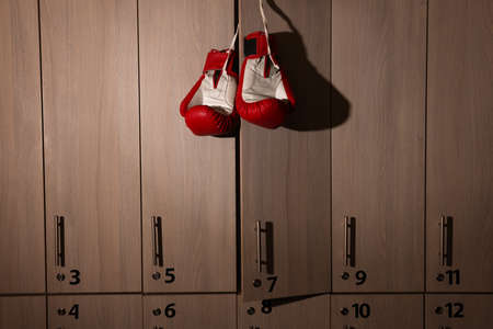 Red boxing gloves hanging on locker door in changing roomの写真素材