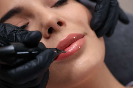 Young woman undergoing procedure of permanent lip makeup in tattoo salon, closeupの写真素材