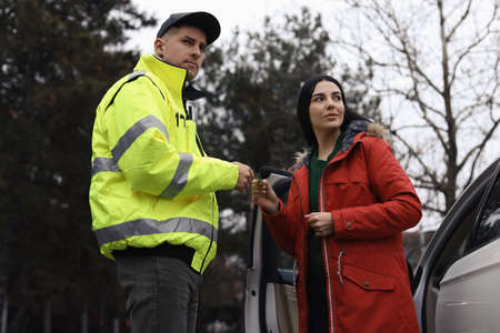 Woman giving bribe to police officer near car outdoors
