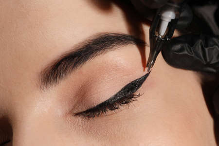 Young woman undergoing procedure of permanent eye makeup in tattoo salon, closeupの写真素材