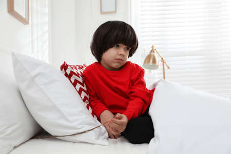 Sad little boy finding tree twig under pillow in bed at home. saint nicholas day traditionの写真素材