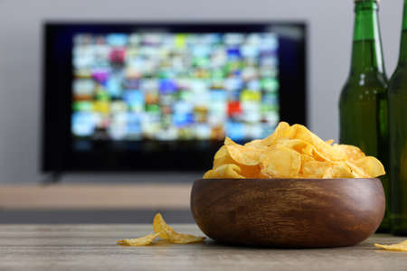Modern TV set indoors, focus on table with chips and beerの写真素材