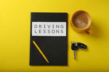 Flat lay composition with workbook for driving lessons on yellow background. Passing license examの写真素材