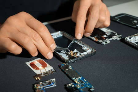 Technician repairing broken smartphone at table, closeupの写真素材