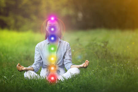 Young woman meditating on green grass. Scheme of seven chakras, illustrationの写真素材