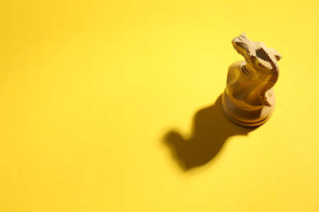 White wooden chess knight on yellow background, above view. Space for textの写真素材
