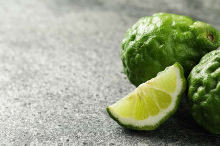 Whole and cut ripe bergamot fruits on gray table, closeup. Space for text