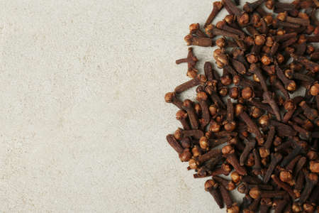 Pile of aromatic dry cloves on white table, flat lay. Space for text