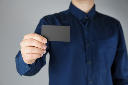 Man holding black business card on gray background, closeupの写真素材