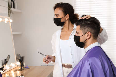 Professional stylist working with client in salon. Hairdressing services during Coronavirus...
