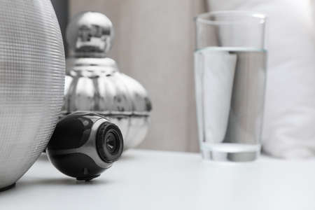 Small hidden camera on white nightstand in bedroom