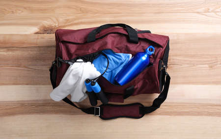 Sports bag with gym stuff on wooden floor, top viewの写真素材