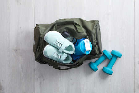 Sports bag with gym stuff and equipment on white floor, flat layの写真素材