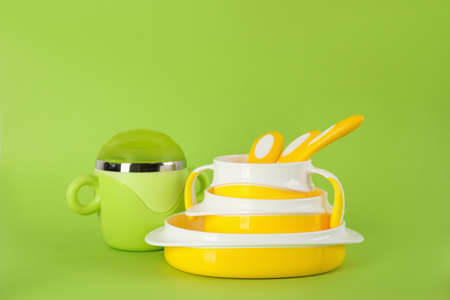 Set of plastic dishware on light green background. Serving baby foodの写真素材