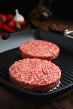 Raw hamburger patties with oil on grill pan, closeupの写真素材