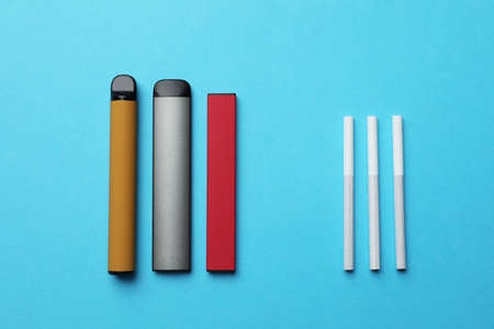 Electronic and regular cigarettes on light blue background, flat layの写真素材