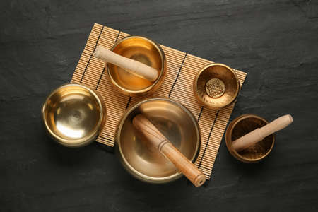 Golden singing bowls with mallets on black table, flat layの写真素材
