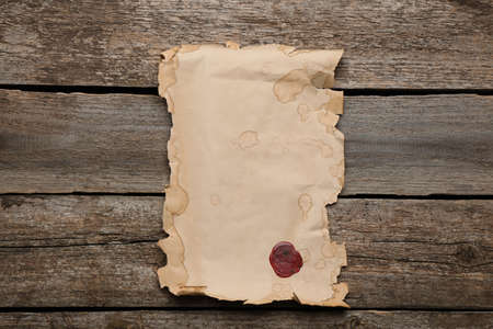 Sheet of old parchment paper with wax stamp on wooden table, top view. space for designの写真素材