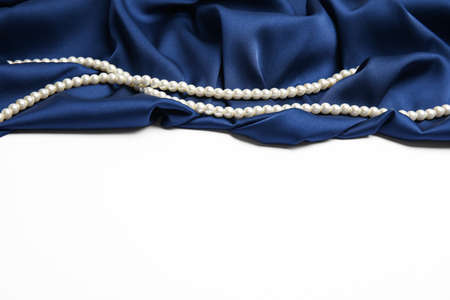 Beautiful pearls and dark blue silk on white backgroundの写真素材