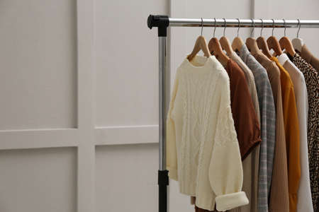Rack with different stylish clothes near gray wall. Space for textの写真素材
