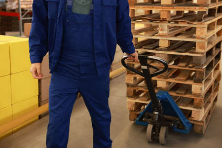 Worker moving wooden pallets with manual forklift in warehouse, closeupの写真素材