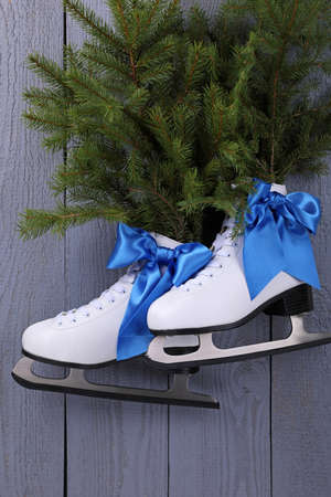 Pair of ice skates with fir branches hanging on gray wooden wallの写真素材