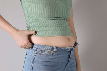 Woman wearing tight clothes on light gray background, closeup. Overweight problemの写真素材