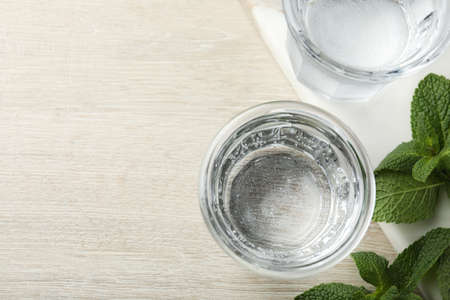 Glasses of soda water and mint on white wooden table, flat lay. Space for text