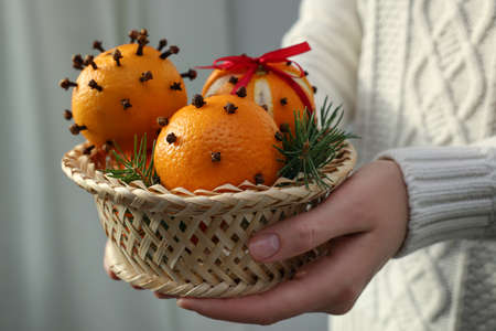 Woman with pomander balls made of fresh tangerines and cloves on light background, closeupの写真素材