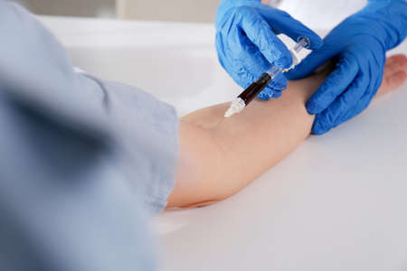 Nurse drawing blood sample from patient in clinic, closeupの写真素材