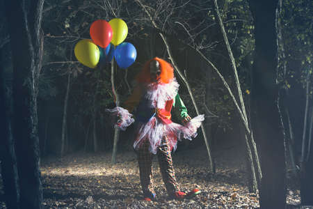 Terrifying clown with air balloons outdoors at night. Halloween party costumeの写真素材