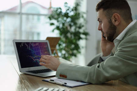 Forex trader talking on phone while working in officeの写真素材