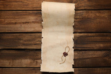 Sheet of old parchment paper with wax stamp on wooden table, top view. space for designの写真素材