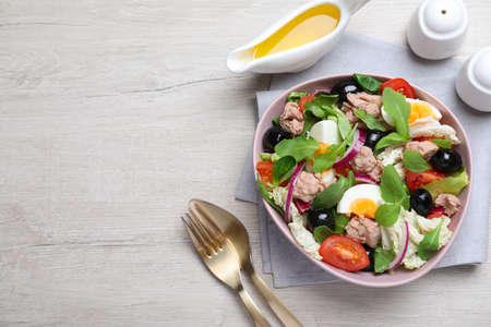 Bowl of delicious salad with canned tuna and vegetables served on white wooden table, flat lay. Space for textの写真素材