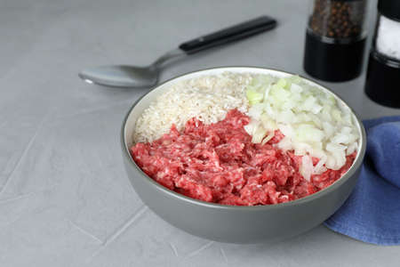 Bowl of forcemeat, chopped onion with rice for preparing stuffed cabbage rolls on light gray tableの写真素材