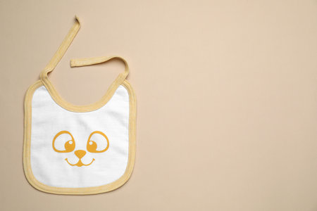 New baby bib on beige background, top view. Space for textの写真素材