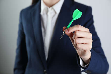 Businesswoman holding green dart on light background, closeupの写真素材