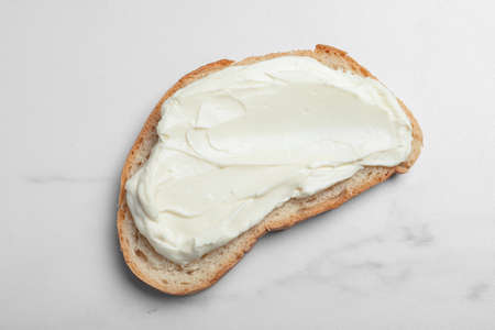 Slice of bread with tasty cream cheese on white marble table, top viewの写真素材