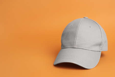Stylish gray baseball cap on orange background. Space for textの写真素材