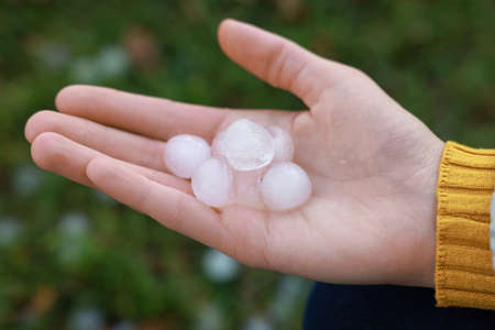 Woman holding hail grains after thunderstorm outdoors, closeup