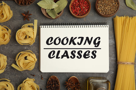 Notebook with inscription Cooking Classes, raw pasta and spices on gray table, flat layの写真素材
