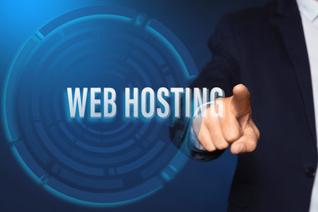 Businessman pointing at phrase WEB HOSTING on virtual screen against blue background, closeupの写真素材
