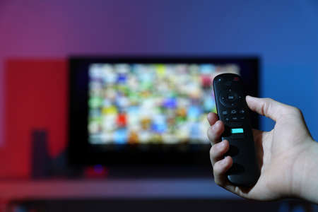 Woman switching channels on TV set with remote control at home, closeupの写真素材