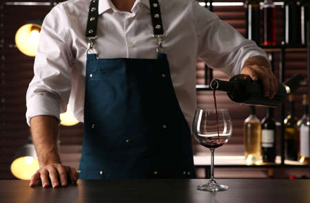 Bartender pouring red wine into glass at counter indoors, closeupの写真素材