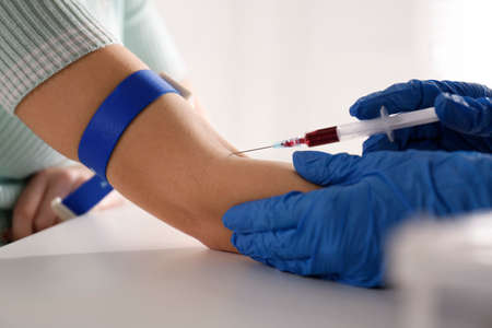 Nurse drawing blood sample from patient in clinic, closeup