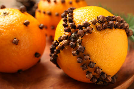 Pomander balls made of tangerines with cloves on wooden plate, closeupの写真素材
