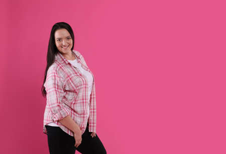 Beautiful overweight woman with charming smile on pink background. Space for text
